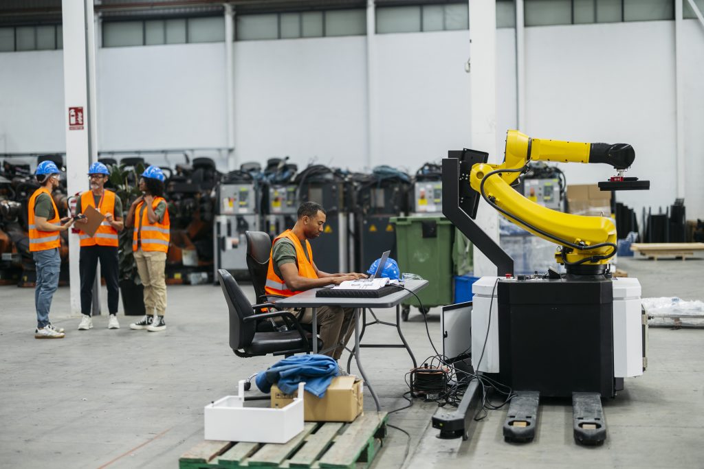 Engineers Collaborating in a Factory and Programming a Robotic Arm for Automation